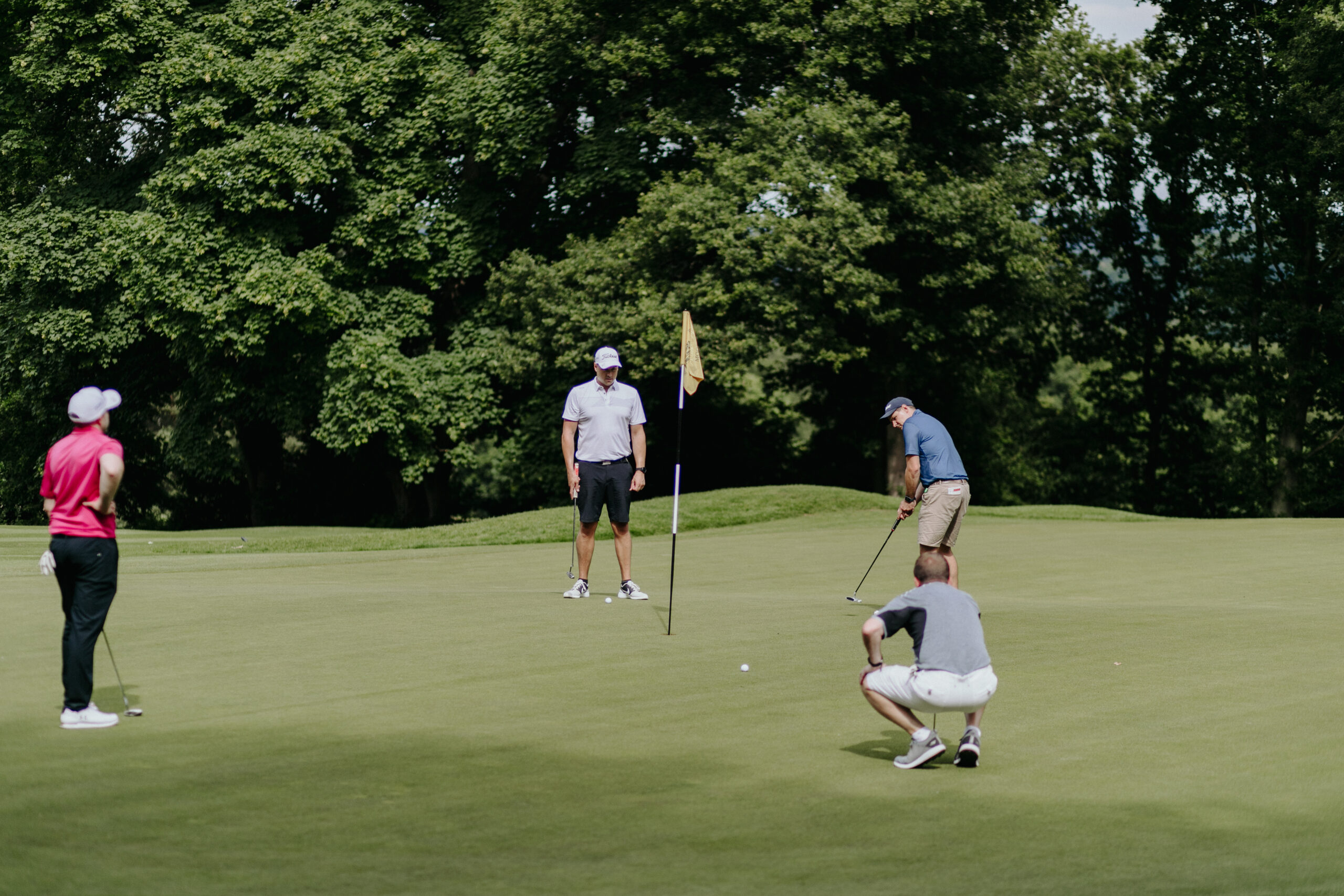 golf_pic23_putt_laying two men watching a third man make a putt