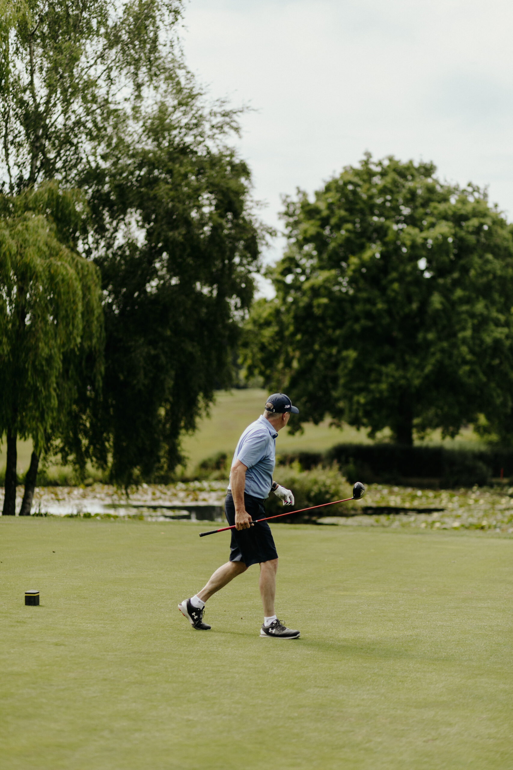 golf_pic26_pond_standing A man walking by a pond on the golf green