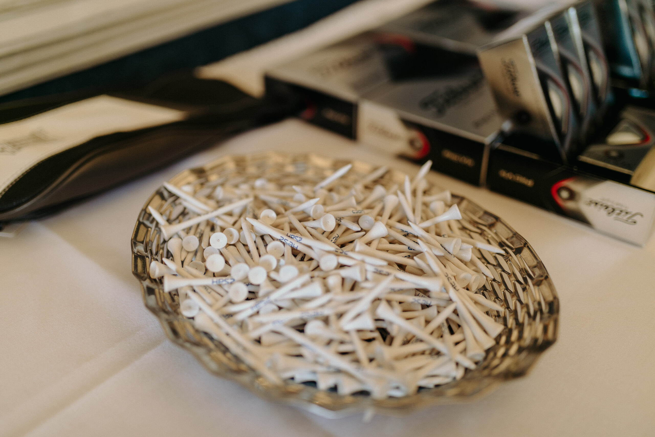 golf_pic4_tees_laying a glass tray filled with white golf tees with 'zsah' printed on them